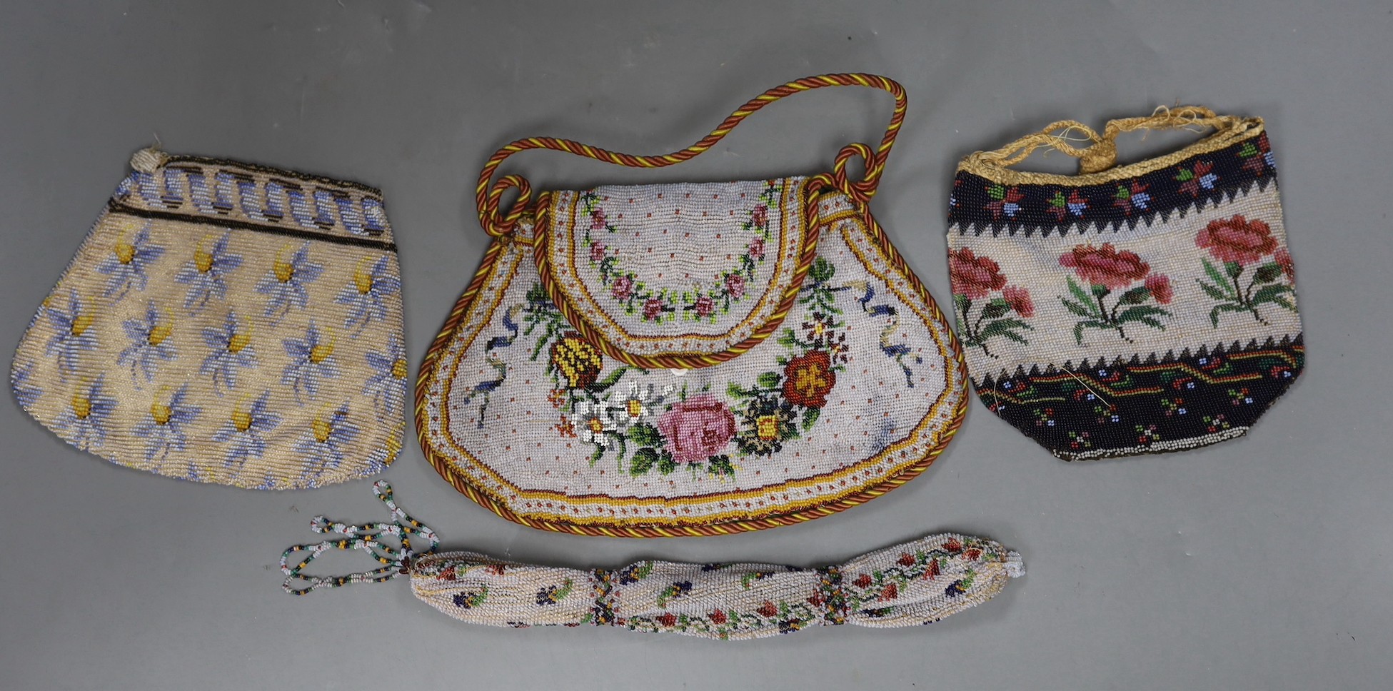 A 19th century shaped floral bead worked bag with corded edging and handle, an unusual bead worked misers purse and two small floral bead bags